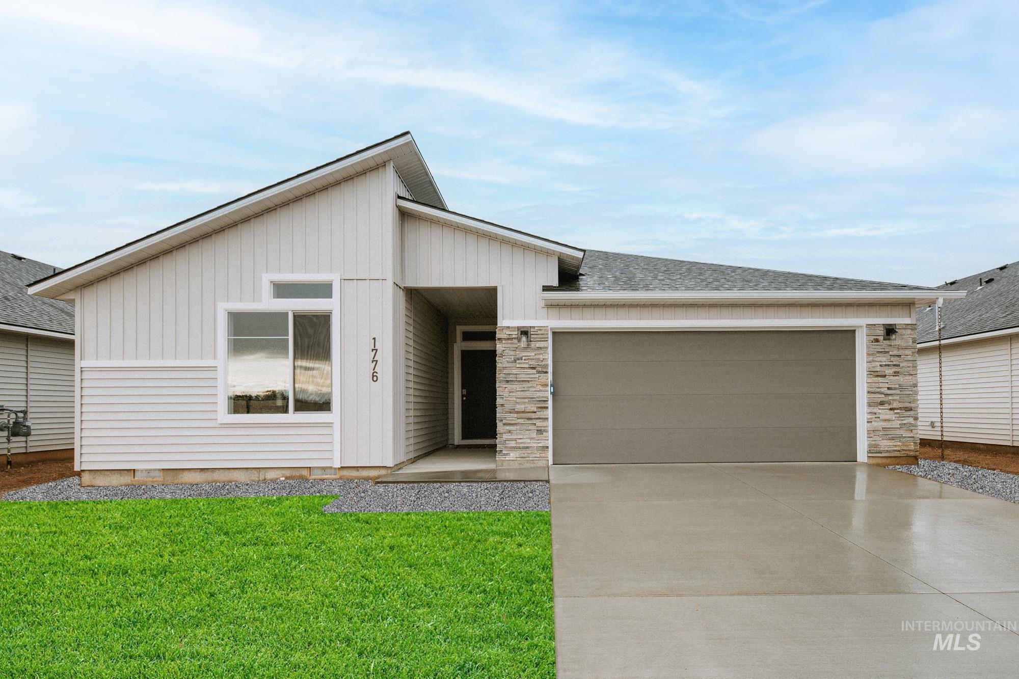 View of front of house featuring concrete driveway, an attached garage, a front yard, and stone siding