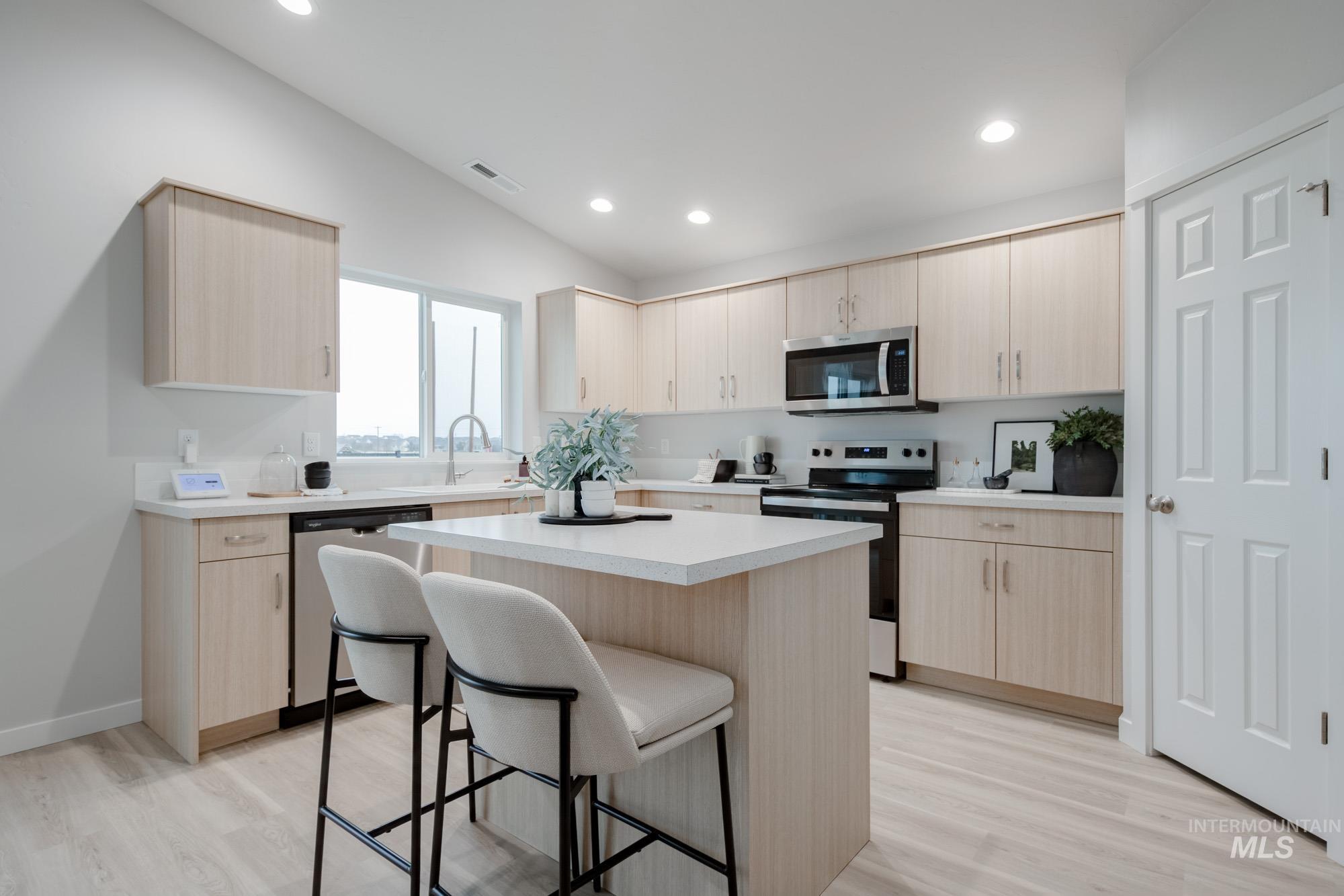 1776 West Unforgettable Street Meridian, ID 83642 - Photo 5 of 28 Kitchen with light brown cabinetry, stainless steel appliances, a kitchen breakfast bar, a kitchen island, and light wood-style floors