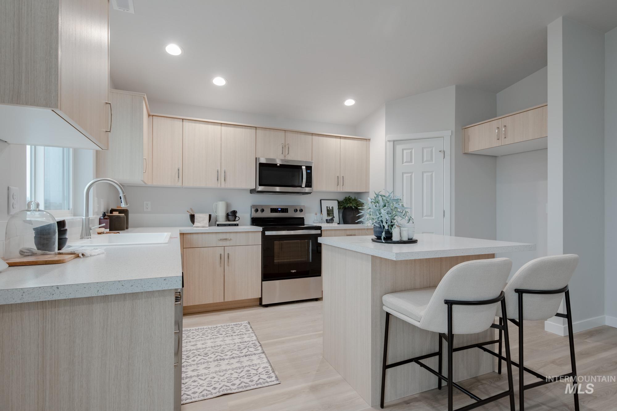 1776 West Unforgettable Street Meridian, ID 83642 - Photo 6 of 27 Kitchen featuring light brown cabinets, a kitchen breakfast bar, appliances with stainless steel finishes, a center island, and recessed lighting