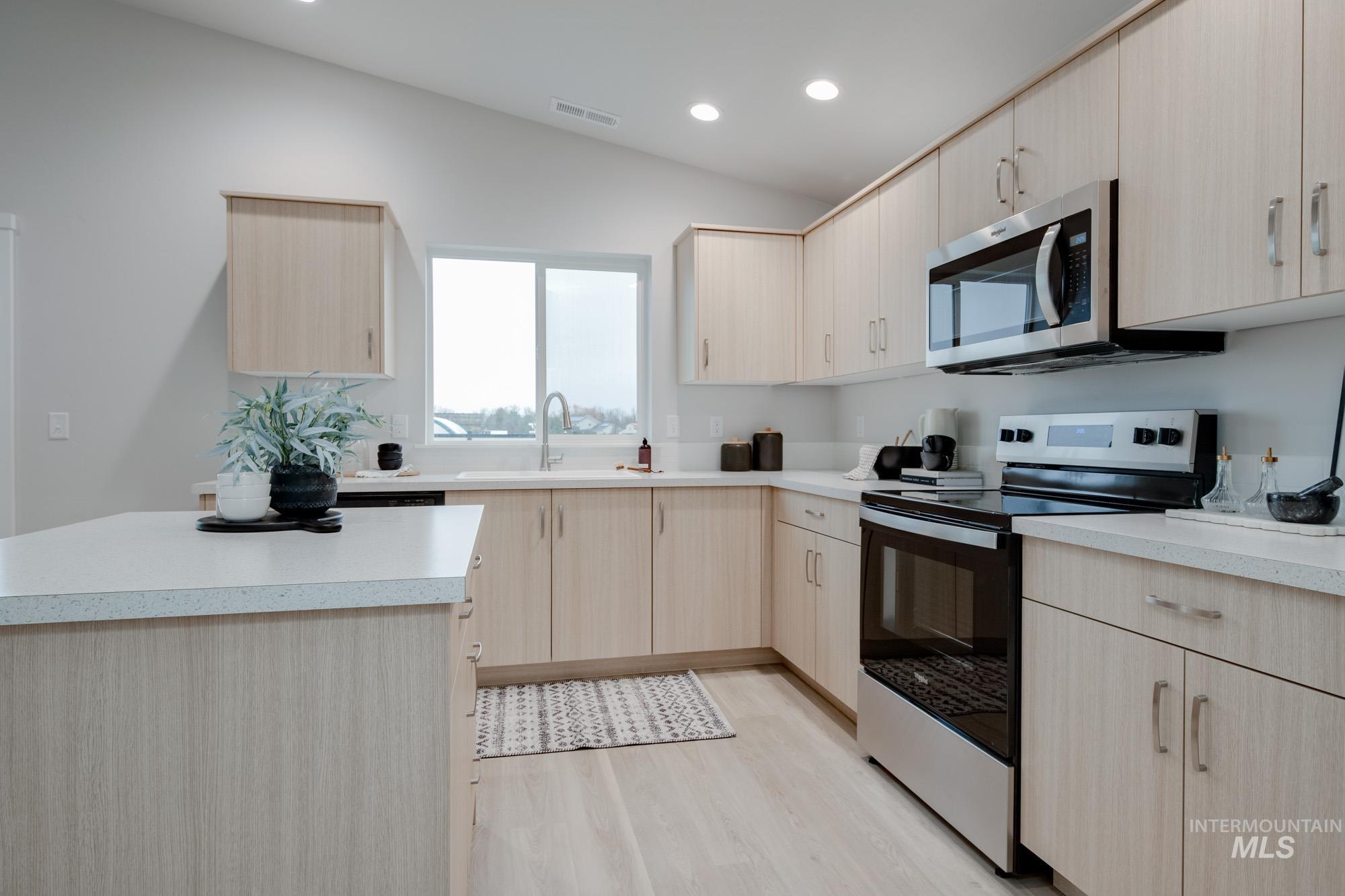 1776 West Unforgettable Street Meridian, ID 83642 - Photo 9 of 28 Kitchen featuring light brown cabinetry, stainless steel appliances, light countertops, vaulted ceiling, and recessed lighting