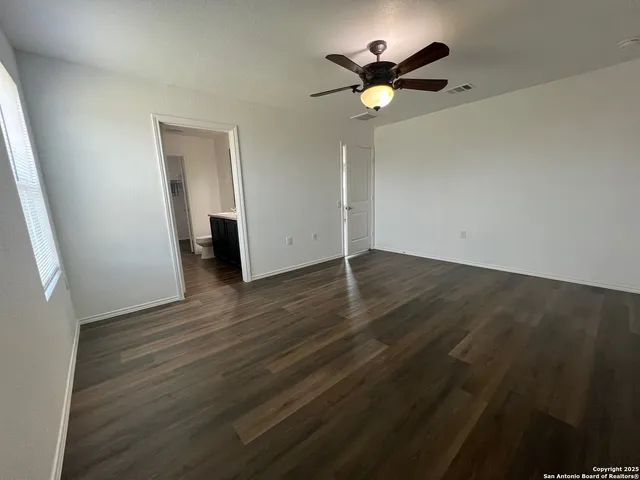 an empty room with wooden floor and a ceiling fan