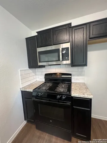 a kitchen with granite countertop cabinets stove and microwave
