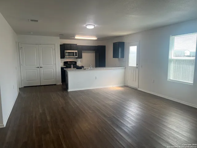 a view of a kitchen with wooden floor and electronic appliances