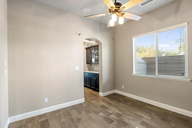 a view of an empty room with window and chandelier fan