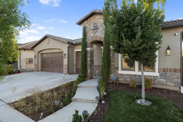 a front view of a house with a garden and trees