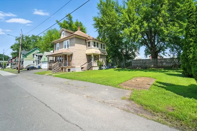 a view of a house with a big yard plants and large trees