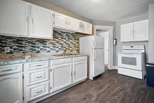 a kitchen with granite countertop white cabinets and white appliances