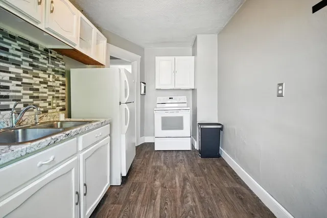 a kitchen with a sink a refrigerator a stove top oven and wooden floor