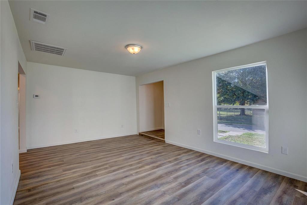 1908 Division Street Greenville, TX 75401 - Photo 6 of 11 a view of an empty room with wooden floor and a window