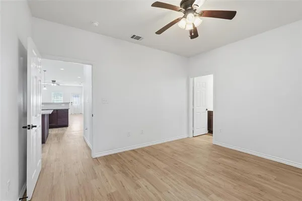 wooden floor in an empty room with a chandelier fan