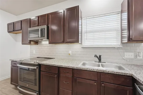 a kitchen with granite countertop cabinets stainless steel appliances and a sink