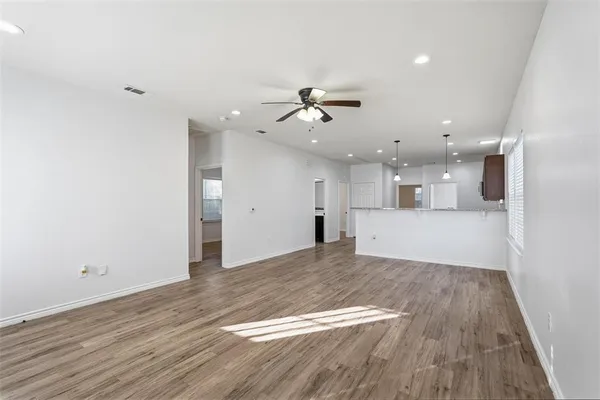 a view of a big room with wooden floor and a kitchen