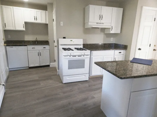 a kitchen with granite countertop a sink stove and cabinets