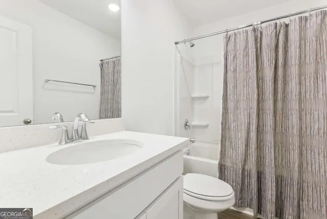 a bathroom with a sink a toilet a mirror and shower curtain