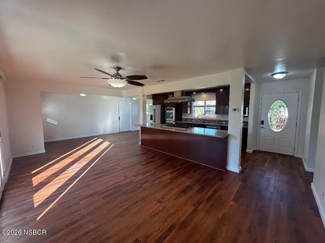 a living room with stainless steel appliances kitchen island granite countertop wooden floors a stove and a sink