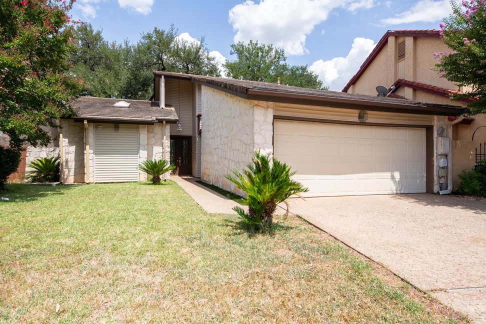 View of front of home featuring concrete driveway, a garage, a front yard, and stone siding