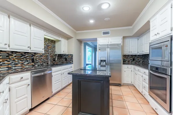 a kitchen with white cabinets and appliances