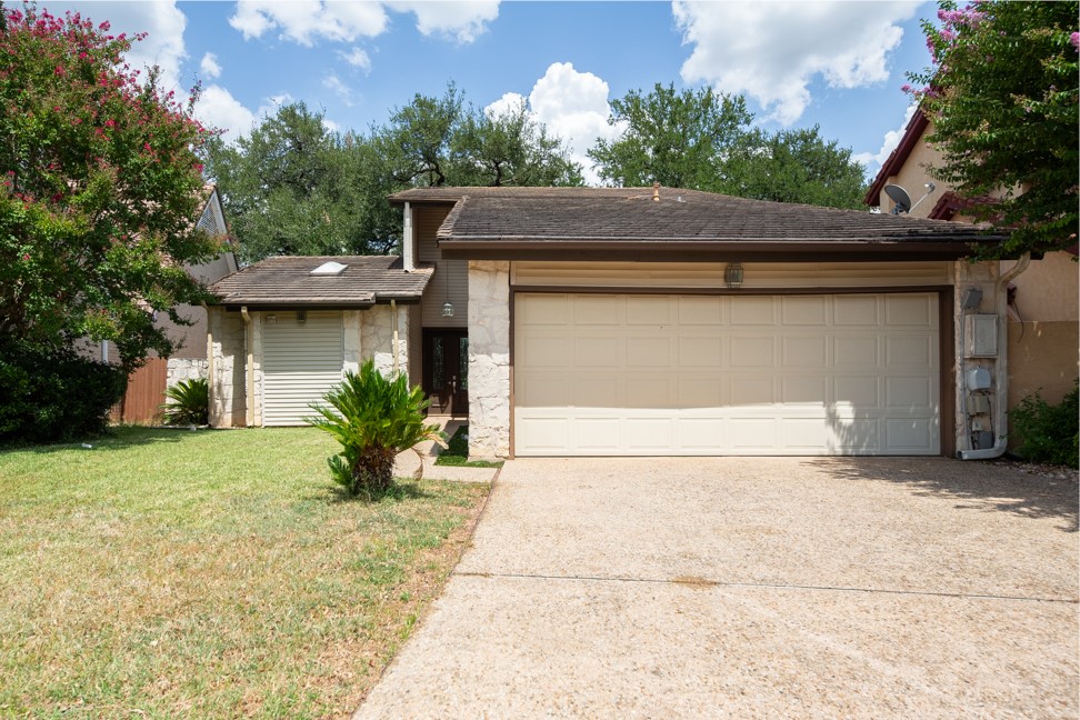 10907 Legends Lane Austin, TX 78747 - Photo 2 of 35 View of front of house with an attached garage, concrete driveway, a front yard, and stone siding