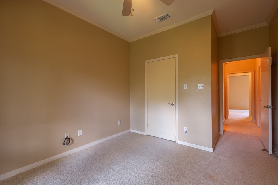 10907 Legends Lane Austin, TX 78747 - Photo 22 of 35 Unfurnished bedroom featuring carpet flooring, ornamental molding, and a ceiling fan