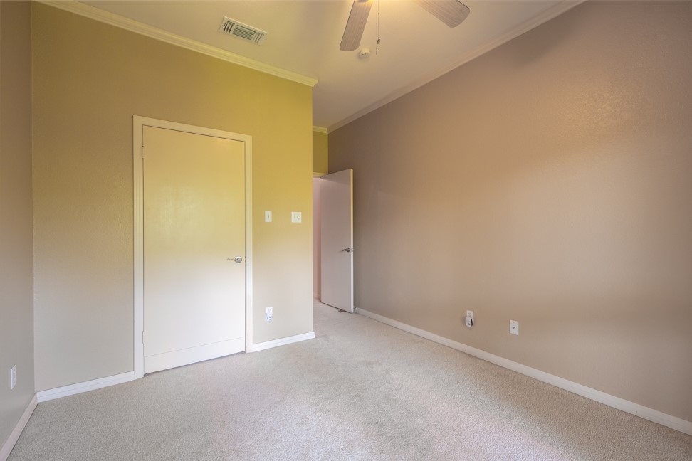 10907 Legends Lane Austin, TX 78747 - Photo 23 of 35 Unfurnished bedroom with light carpet, ornamental molding, and ceiling fan