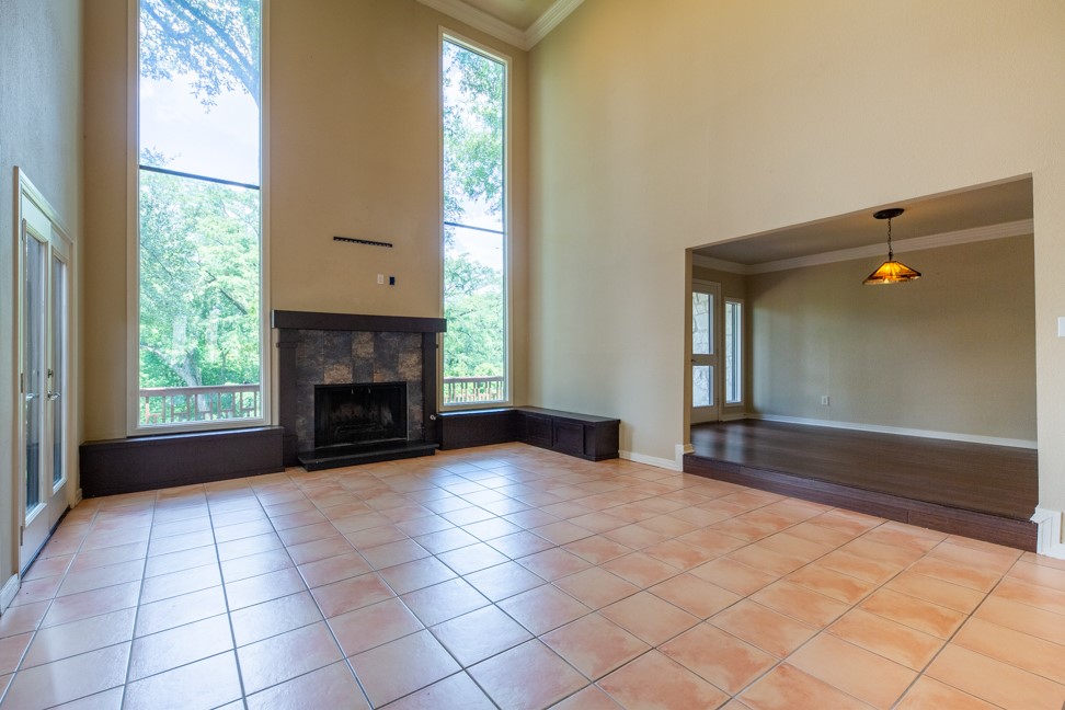 10907 Legends Lane Austin, TX 78747 - Photo 4 of 35 Unfurnished living room with a high ceiling, crown molding, plenty of natural light, a fireplace, and light tile patterned floors