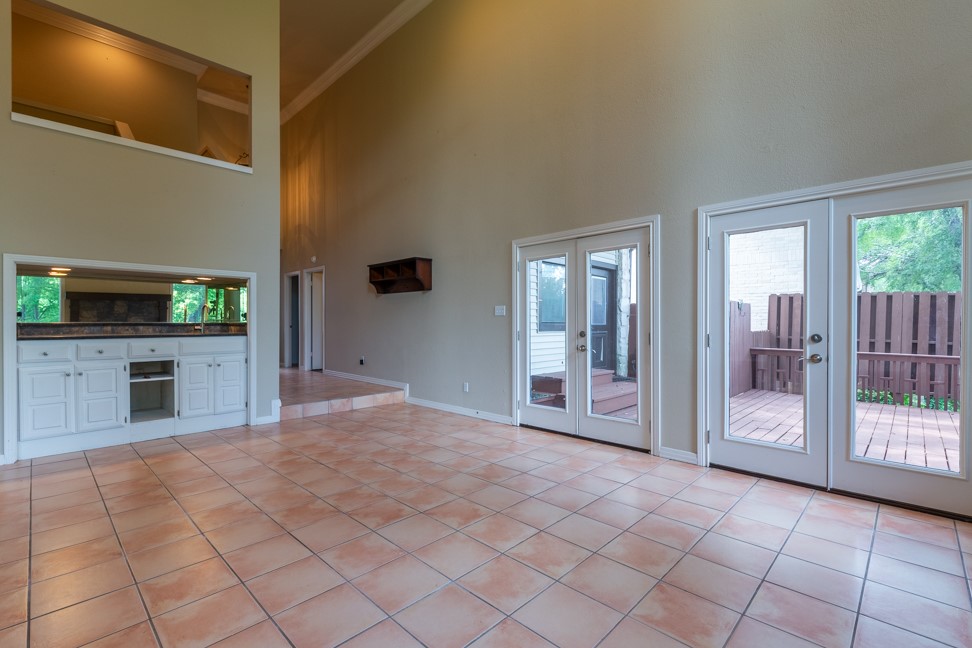 10907 Legends Lane Austin, TX 78747 - Photo 6 of 35 Unfurnished living room featuring french doors, ornamental molding, light tile patterned floors, and a towering ceiling