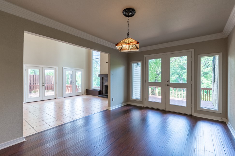 10907 Legends Lane Austin, TX 78747 - Photo 9 of 35 Unfurnished living room featuring french doors, ornamental molding, plenty of natural light, wood finished floors, and a fireplace with raised hearth