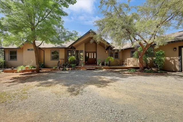 a backyard of a house with table and chairs under an umbrella