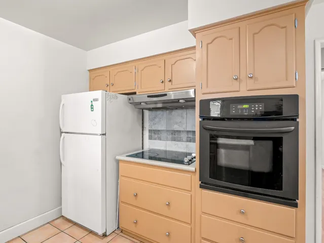 a kitchen with granite countertop white cabinets and refrigerator
