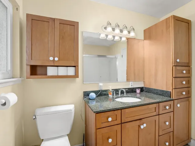 a bathroom with a granite countertop sink a toilet and a mirror