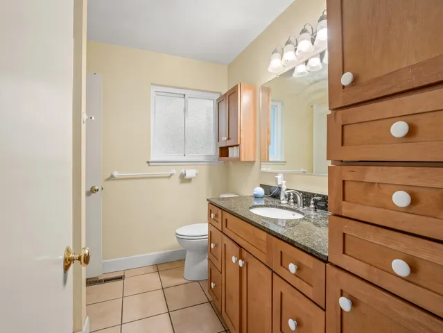 a bathroom with a granite countertop sink toilet and mirror