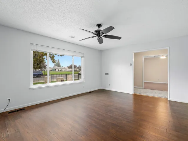 a view of empty room with wooden floor and fan