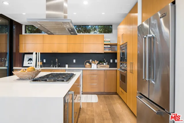 a kitchen with stainless steel appliances granite countertop a refrigerator a oven and a sink with wooden floor