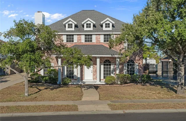 a view of a white house with large windows and a tree