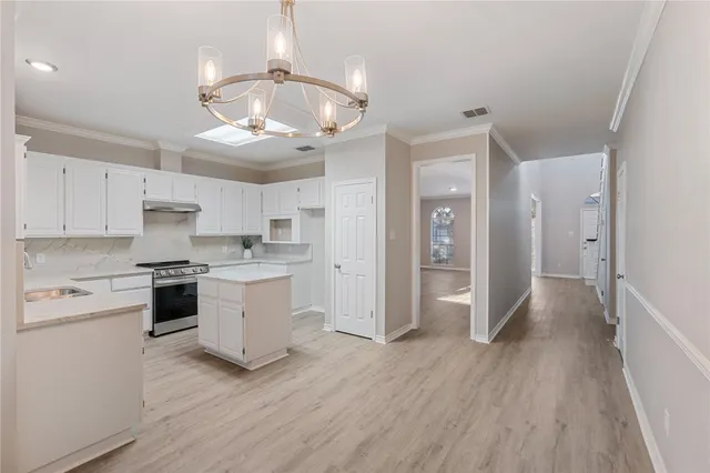 a kitchen with a hard wood floor white cabinets and stainless steel appliances