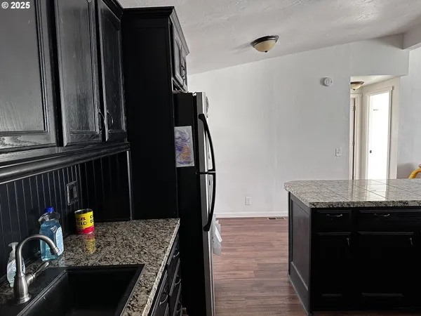 a kitchen with granite countertop a refrigerator a stove and wooden cabinets