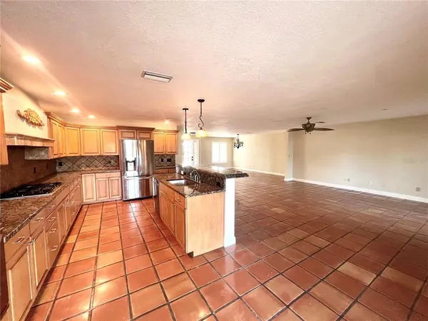 a large kitchen with kitchen island granite countertop a sink and a stove top oven