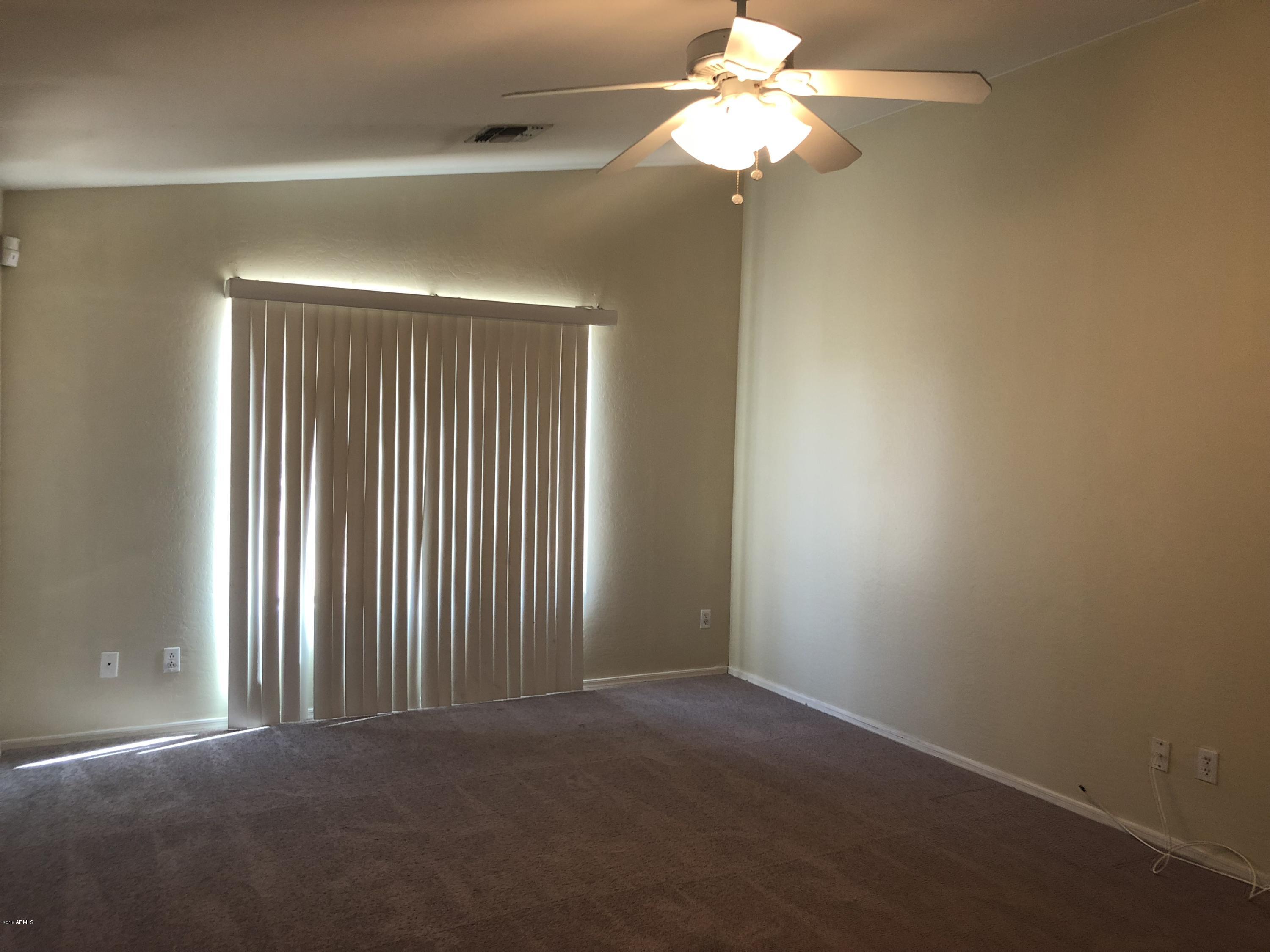 2321 West Maldonado Road Phoenix, AZ 85041 - Photo 32 of 44 an empty room with a chandelier fan and windows
