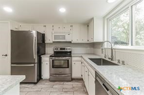 12011 Scribe Drive Austin, TX 78759 - Photo 5 of 14 a kitchen with granite countertop white cabinets and stainless steel appliances