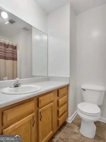 a bathroom with a granite countertop toilet sink and mirror