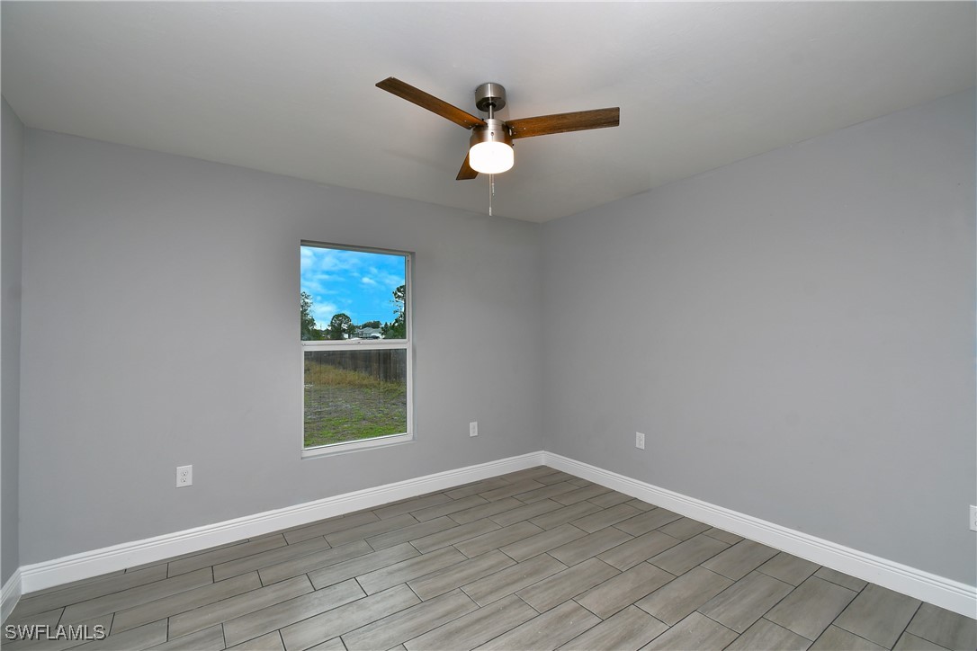 3103 Vera Avenue South Lehigh Acres, FL 33976 - Photo 22 of 36 an empty room with wooden floor and ceiling fan