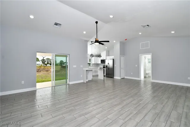 a view of an empty room with window wooden floor and kitchen view