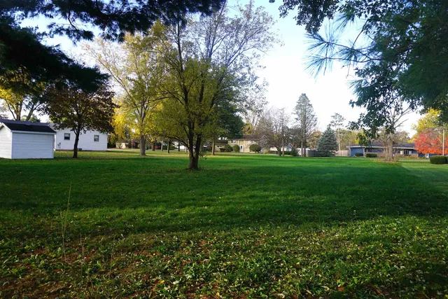 a view of grassy field with benches and trees all around