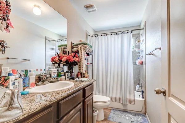 a bathroom with a granite countertop sink a toilet and shower curtain