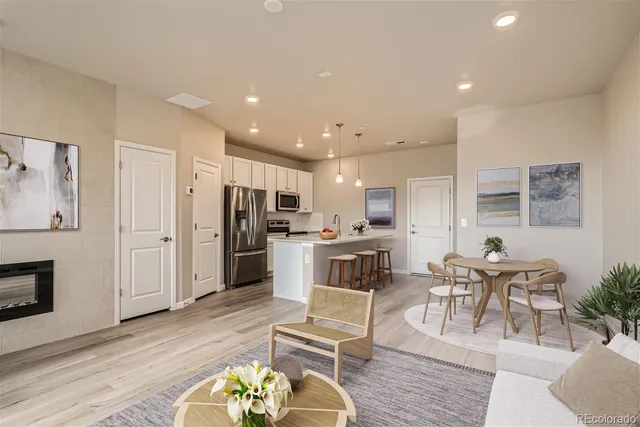 a kitchen with stainless steel appliances kitchen island granite countertop a refrigerator a stove a sink a dining table and chairs with wooden floor