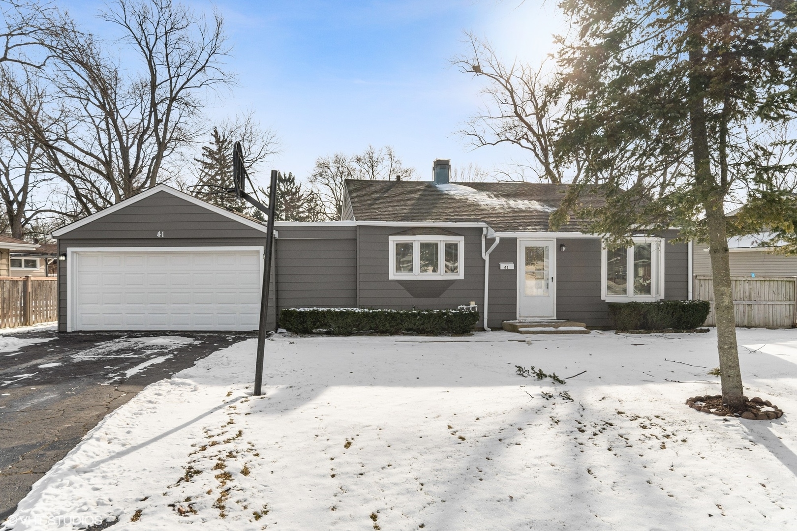 a front view of a house with a yard covered in snow