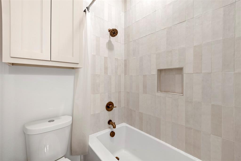 861 Brindley Road Maypearl, TX 76064 - Photo 24 of 36 White subway tile shower surround with integrated niche, modern white bathtub, and bronze fixtures