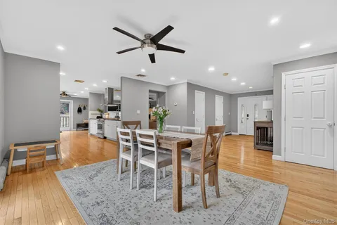 a dining room with stainless steel appliances kitchen island granite countertop a table chairs and a living room view