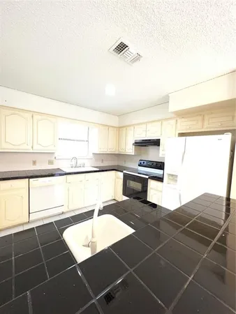 a kitchen with granite countertop a stove a sink and a microwave