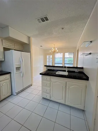 a large white kitchen with a sink and dishwasher a refrigerator with white cabinets